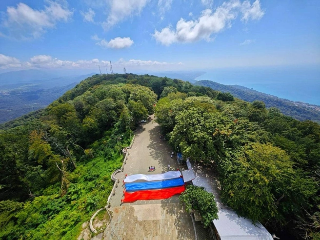 Полотна в цветах триколора развернули на самой высокой точке города — башне на горе Ахун | Источник: sochi.ru