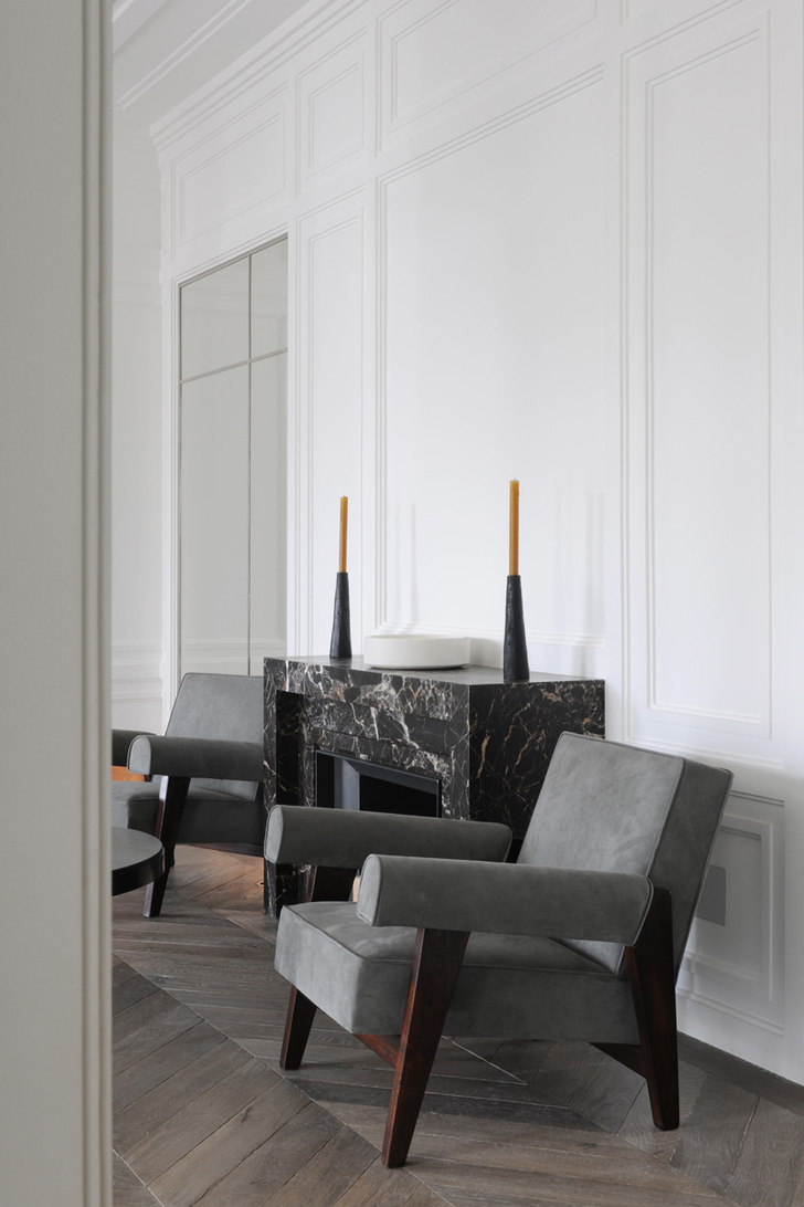 Интерьер гостиной в белом цвете. Камин из мрамора выполнен в духе ар-деко. Кресла — реплики работ Ле Корбюзье и Пьера Жаннере.