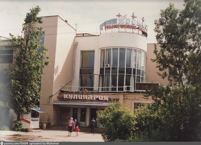 В 90-е здание стало называться «комбинат питания „Космос“», появилась характерная вывеска. Снято в период 1993–1995 годов | Источник: департамент социального развития ГКНЦП и. Хруничева, предоставил Царев Александр Георгиевич, загружено на Pastvu.com пользователем Muhomor