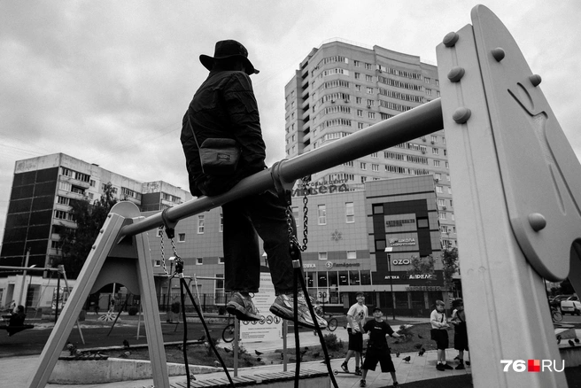 Тёмный силуэт ребёнка в шляпе, сидящего на перекладине, выделяется на фоне яркого неба | Источник: Александр Куренной / 76.RU