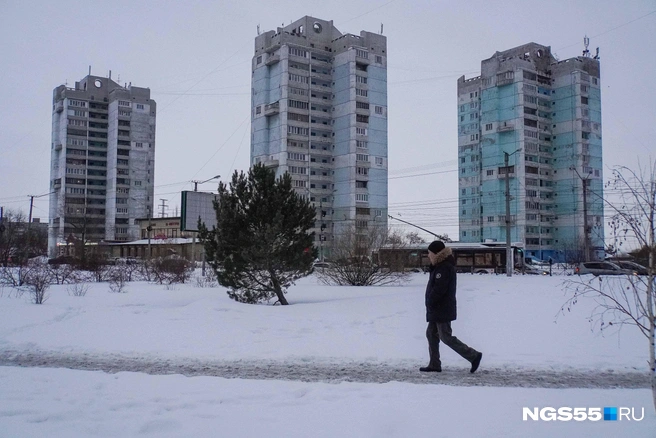 Омич в черном пуховике кинематографично сливается с окружающей обстановкой. Единственный акцент образа — мех на капюшоне | Источник: Евгений Софийчук / NGS55.RU