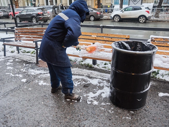 Дворники убирают снег со скамеек.