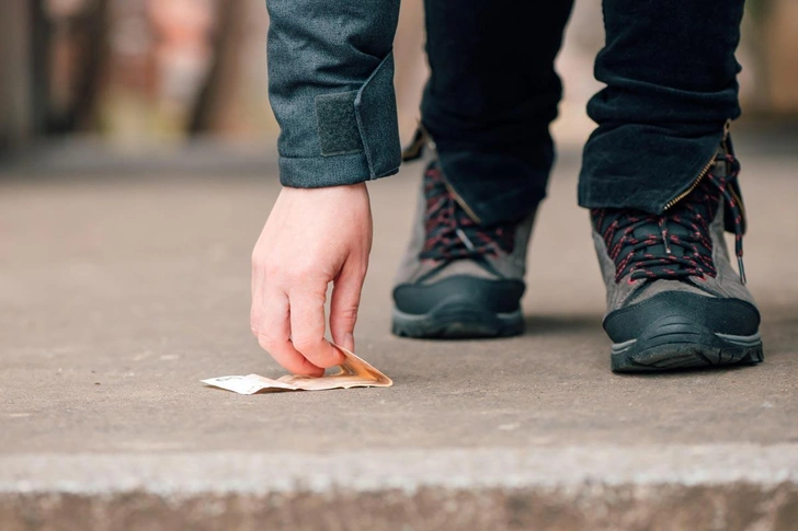 Человек подбирает деньги, найденные на тротуаре | Источник: Igor Stevanovic / Alamy via Legion Media