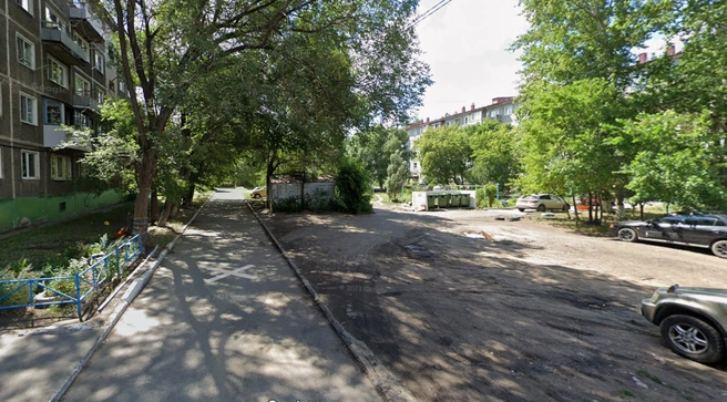 Во дворе стоят мусорные баки и железные гаражи | Источник: Google Maps