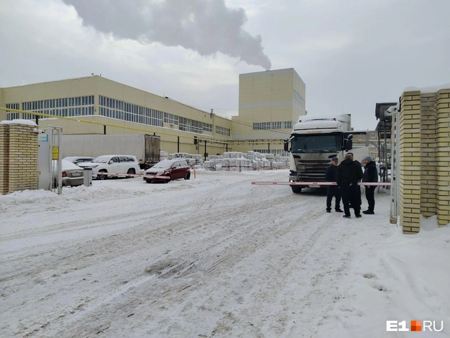 Дальнобойщики и охранники что-то бурно обсуждают на заводской проходной | Источник: Роман Марьяненко / E1.RU