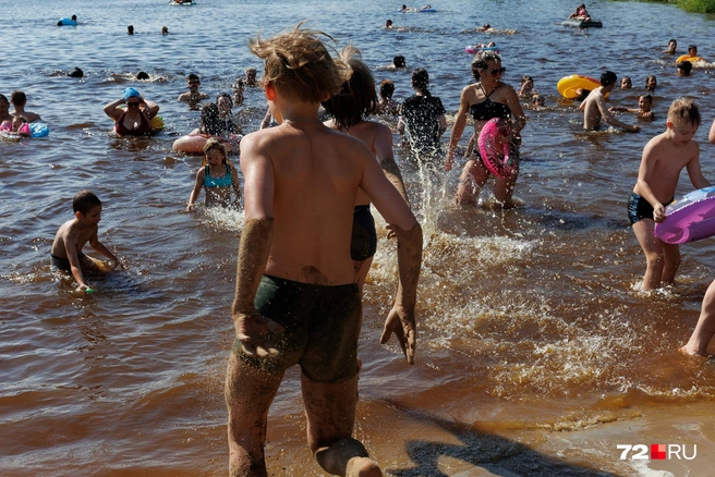 Грязи, как в прошлом году, нет. Поэтому дети измазываются песком на берегу и бегут в воду  | Источник: Ирина Шарова / 72.RU 