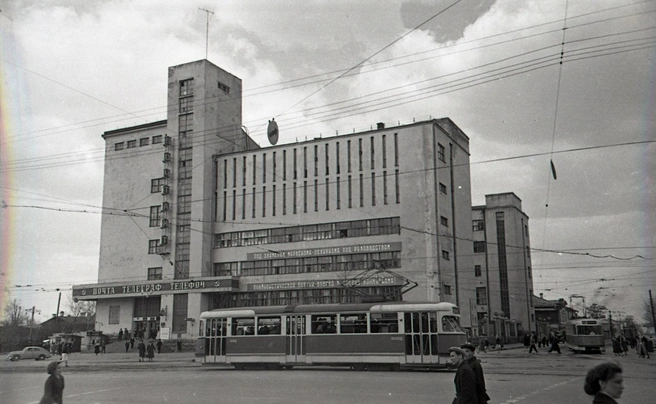 В шестидесятые у входа в Главпочтамт висели часы. С левой стороны был расположен сквер и стоянка такси. На снимке видно, как трамвай поворачивает направо, на улицу Толмачёва. Сейчас этой трамвайной ветки уже нет.