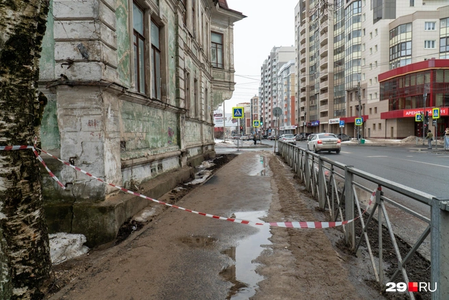 Дом огородили с нескольких сторон, прохожим приходится поднимать ленту, чтобы пройти | Источник: Кристина Полевая