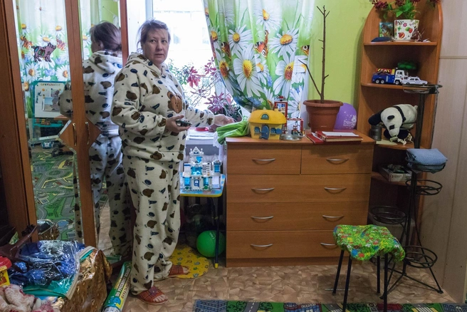 Екатерина убирает штору, а за ней подоконник, застеленный полотенцами | Источник: Сергей Федосеев