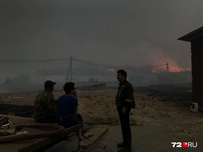 Работники фермы наблюдают, как горят постройки. Они тут не помогут — пламя очень сильное | Источник: Артур Галиев