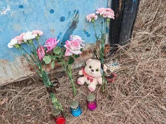 Жители поселка несли цветы и игрушки к месту нападения собак на 12-летнюю девочку. На гараже остался след от ее окровавленной руки | Источник: @nerungri_1 / Telegram