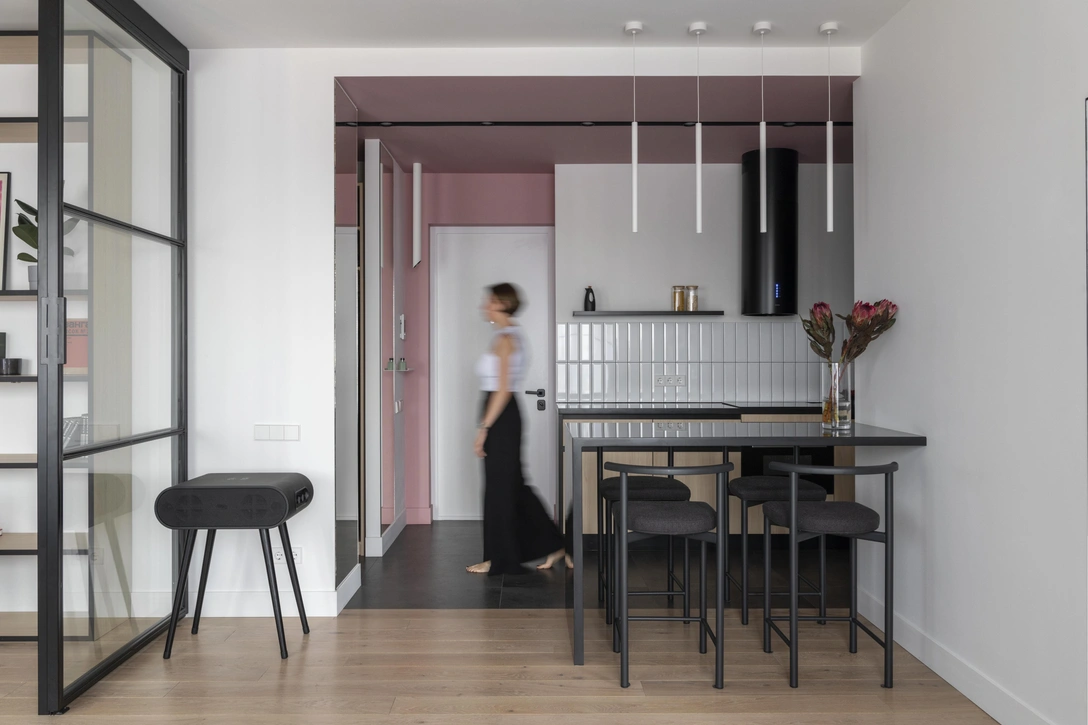 Кухня-гостиная, фрагмент. В зоне прихожей и кухни поверхности покрашены в одинаковый приглушенно-розовый цвет, что визуально отделяет пространство от смежной гостиной, так как между этими помещениями нет перегородок и дверей. | Источник: Даниил Анненков