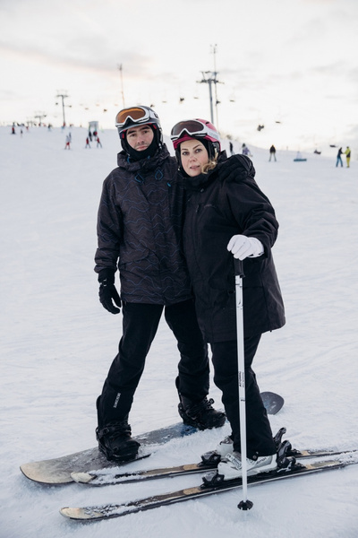 Мужчина на сноуборде и женщина на лыжах