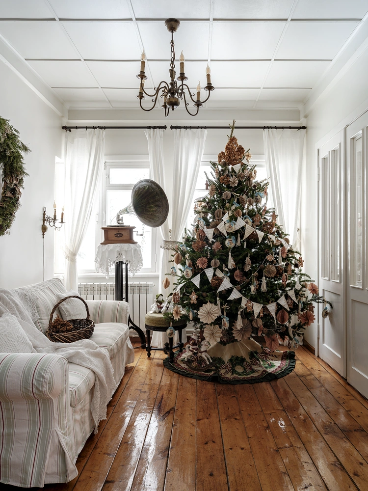 Новогодний декор — работа флориста Веры Марковой, @verflower. Почти все игрушки на елке самодельные. Бумажные украшения вырезаны из крафта пудровых оттенков, гирлянды собраны из шнуров макраме, лесных шишек и нотной бумаги, вымоченной в кофе. Деревянные игрушки на шелковых голубых лентах, Светлана Черкашина, @deko_lanka. | Источник: Дина Александрова