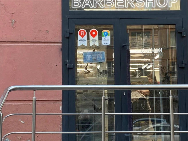 Мужская парикмахерская на улице Урицкого декорировала дверь искусственной паутиной, а на стекле разместила изображения летучих мышей и рук. | Источник: Анастасия Хрипушина/NGS.RU