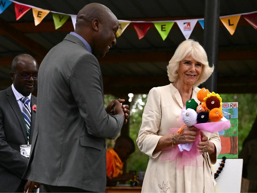 Королева Великобритании Камилла на рынке в Кении с букетом самодельных цветов от девочки, 1 ноября 2023 год | marieclaire.ru