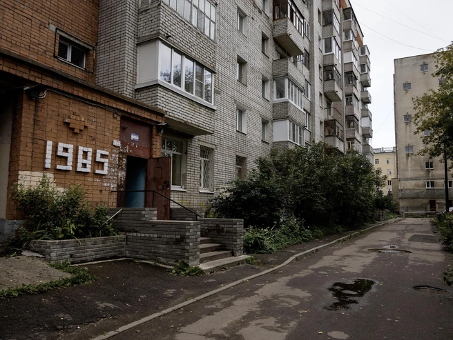 У подъезда выложен год основания дома, а во дворе — лужи и высокие кусты | Источник: Александр Куренной / 76.RU