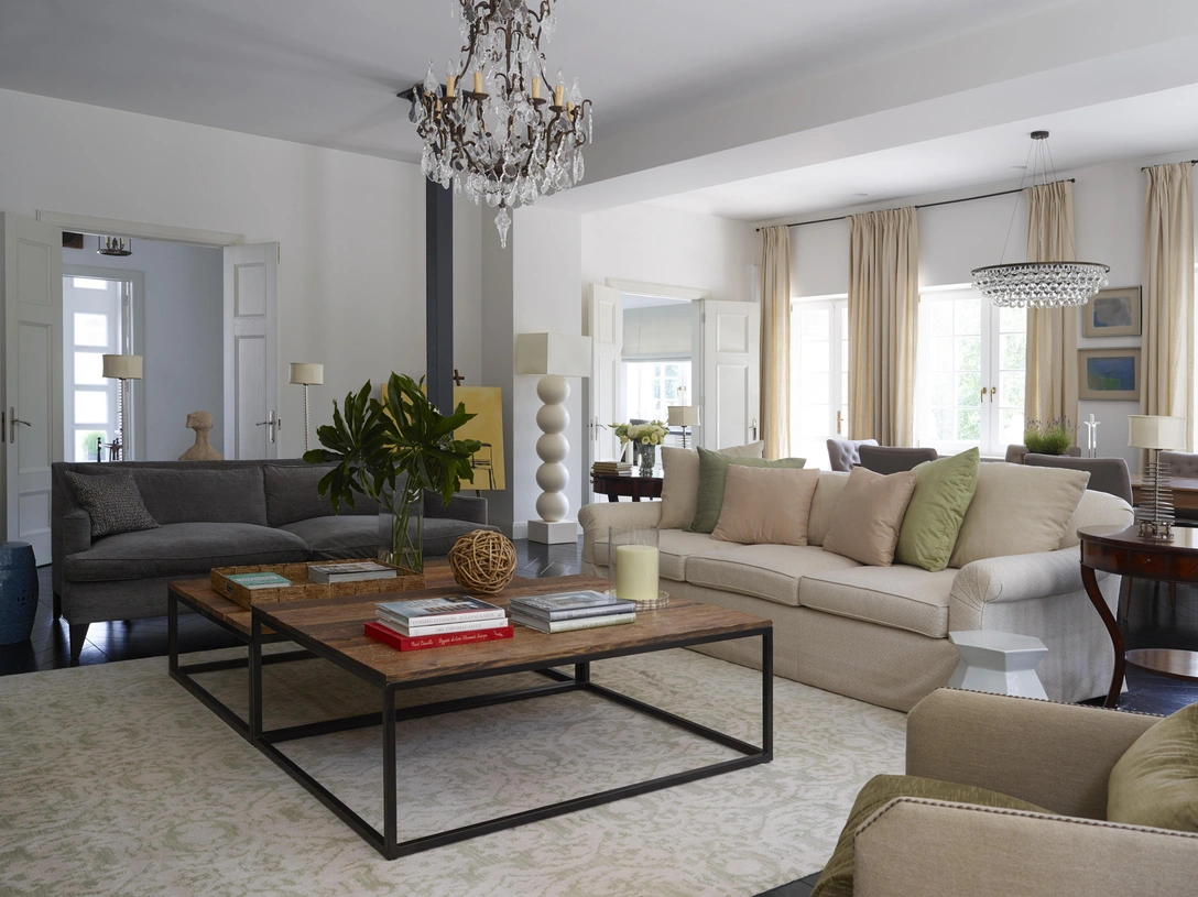 Гостиная визуально отделена от столовой выстроенной с этой целью прямоугольной аркой. Журнальные столики со столешницами из антикварных досок, светлый диван и столики по бокам от него, все — Ralph Lauren Home. Обивка дивана, Beacon Hill, подушки в тканях от Lee Jofa и Robert Allen. Бархатный диван цвета графита, Montauk. Шерстяной ковер, дизайн Oscar de la Renta для Elson & Co. Настольные лампы, Ochre. Люстра, Labyrinthe. | Источник: Ричард Пауэрс (Richard Powers)