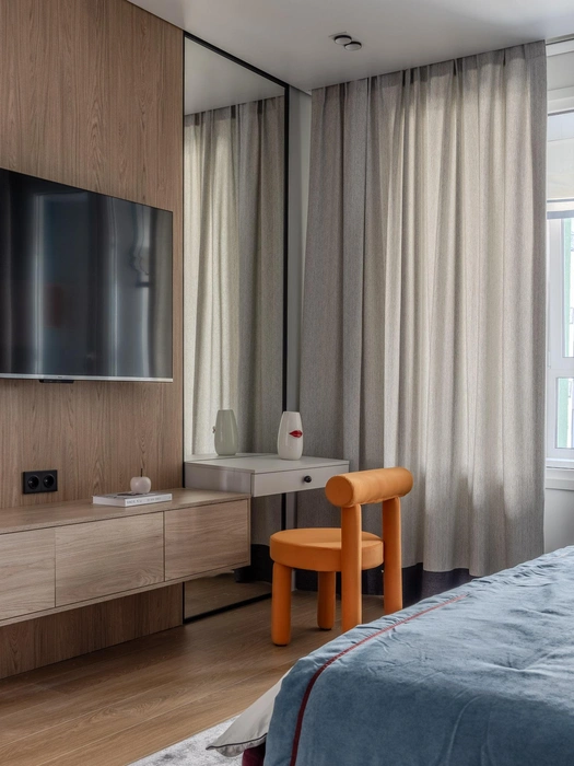 Стену напротив кровати полностью занимает мебельная конструкция, которая состоит из книжного шкафа, подвесной ТВ-тумбы, туалетного столика и зеркал во всю высоту помещения | Источник: Роман Спиридонов / myDecor