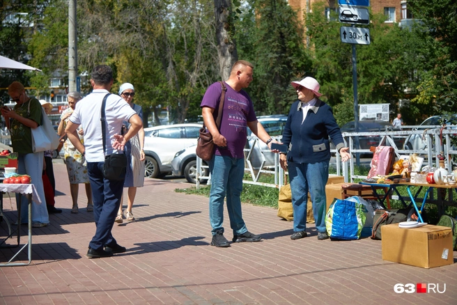 — Люди жалуются, что вы вытаскиваете сюда свое барахло, устраиваете здесь рынок, — решительно выговаривает бабушке мужчина в футболке цвета баклажана | Источник: Роман Данилкин / 63.RU