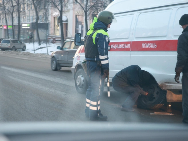 Полицейский помог бригаде скорой помощи, у которой возникла проблема с колесом | Источник: Михаил Шилкин