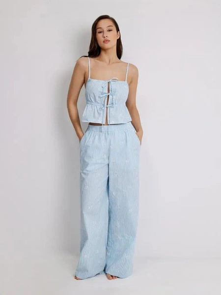 Женские домашние брюки Infinity LingerieХлопковые брюки в голубую полоску подойдут для дома, сна и спокойных вечеров: они мягко сидят на талии за счет резинки и не стесняют движения. Белая цветочная вышивка и карманы в боковых швах добавляют им чуть более «одежного» вида, в таких брюках комфортно и просто отдыхать, и встретить гостей на домашней пижамной встрече.