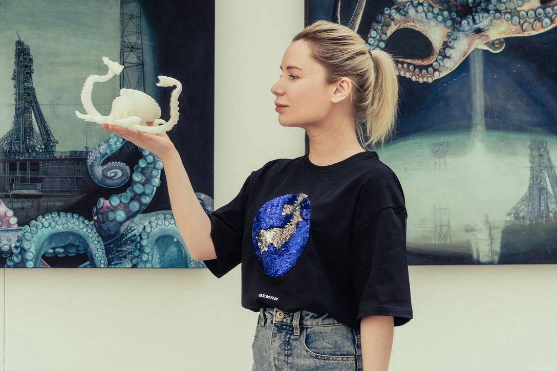 Художник Настя Миро с осьминогом Octo-Pax в руках на фоне своих картин. | Источник: архивы пресс-служб