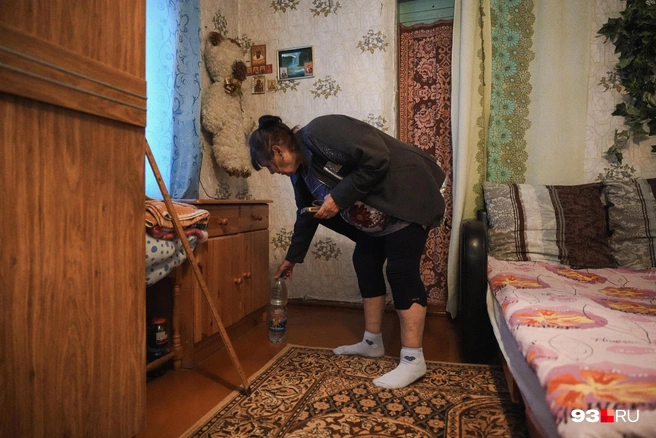 Ольга Анатольевна показывает бутылку, которая ее будит, если дом шатается | Источник: Дарья Паращенко / 93.RU