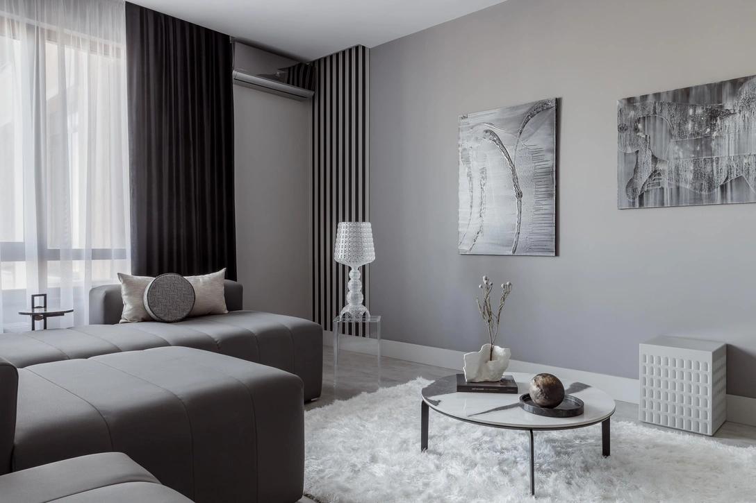 Кухня-гостиная, фрагмент. Табурет, пуф и настольная лампа, все — Kartell. На стене работы Игоря Михайленко. Ковер и столик, «Мир ковров». На столике ваза Юлии Деминой и шар Татьяны Солодовниковой. Краска, Mylands. Молдинги и плинтус, Orac Décor. | Источник: Михаил Чекалов. Стиль: София Калбазова