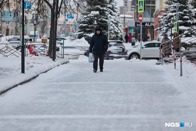 Некоторым людям приходится замедлять шаг, чтобы не упасть на скользком тротуаре | Источник: Александр Ощепков / NGS.RU