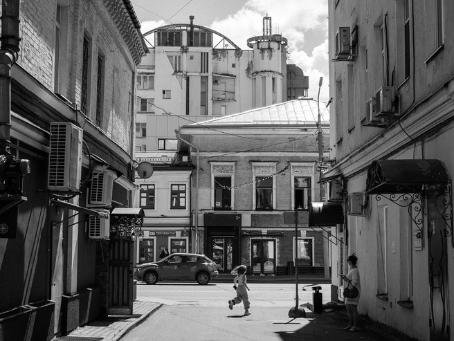 Среди множества деталей фасадов выделяется девочка, которая бежит по центру улицы в солнечном свете | Источник: Александр Куренной / 76.RU