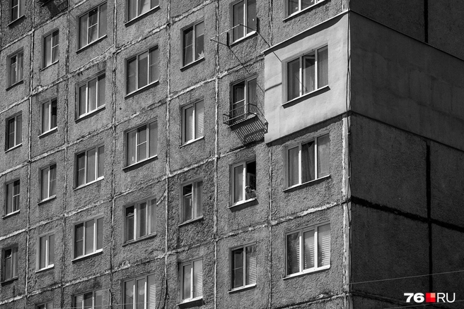 Ровные ряды окон и строгие линии фасада оживляет человек, выглядывающий из окна | Источник: Александр Куренной / 76.RU
