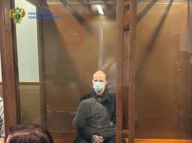 Молодой человек предстал перед судом в черном пальто и рубашке, а на ладони виднеется татуировка | Источник: ПРОКУРАТУРА МОСКВЫ / T.me