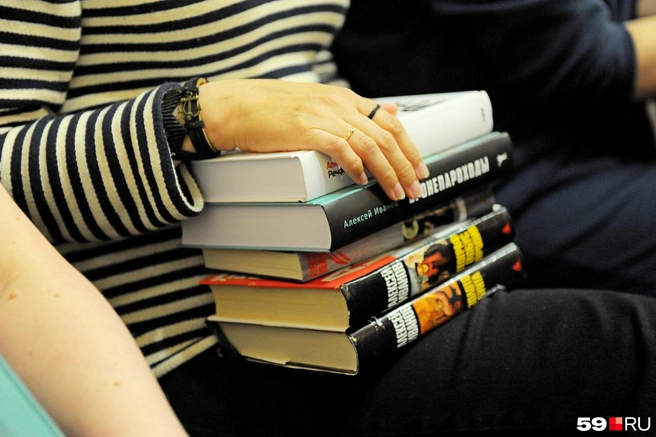 Кажется, стопка книг Алексея Иванова станет еще больше (в кадре, конечно, не все произведения писателя — это книги, с которыми приходила читательница на встречу) | Источник: Ирина Тропина / 59.RU