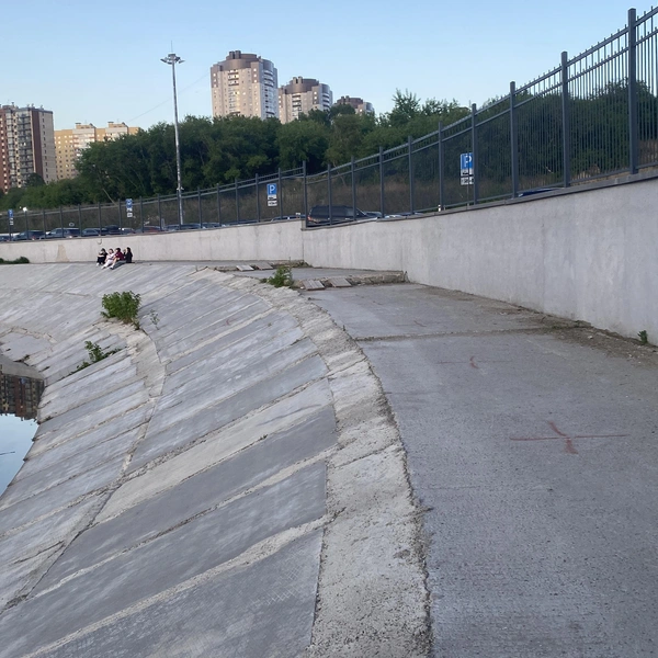 Сейчас на бетонном склоне есть деревянные дорожки и амфитеатр, раньше берег был неблагоустроен | Источник: ГК «Брусника»