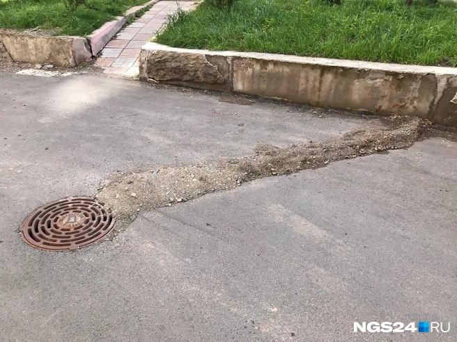 Ограждение из песка, которое, вероятно, должно блокировать поток воды и направлять в колодезный люк | Источник: Дмитрий Мамаев / NGS24.RU