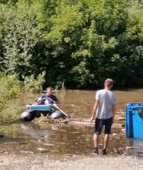 Люди спасают имущество на лодках. На снимке мужчина, который переправляет ванночку для малыша и другие необходимые младенцу вещи | Источник: читатель 72.RU