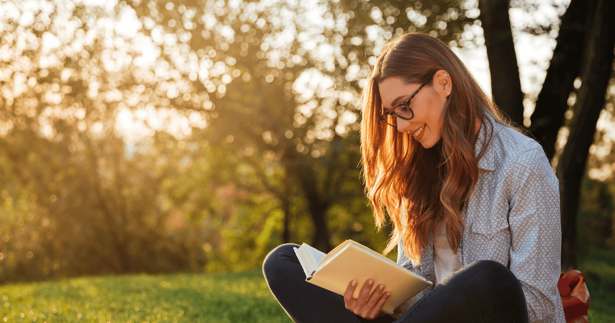 Девочка с книжкой. Девушка с книгой на природе. Девушка стеснительно прячет книгу. Девушка сидит с книгой. Девушка в парке с книгой.
