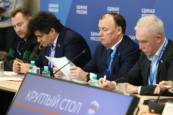 Алексей Орлов изучает документ на форуме в Екатеринбурге, слева от него готовятся к выступлению депутат ЗакСО Вячеслав Брозовский и бывший мэр Екатеринбурга сенатор Александр Высокинский | Источник: Владислав Лоншаков / E1.RU