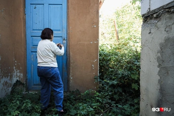 Хозяйка на фоне брошенного ей дома, внутри небезопасно | Источник: Дарья Паращенко / 93.RU