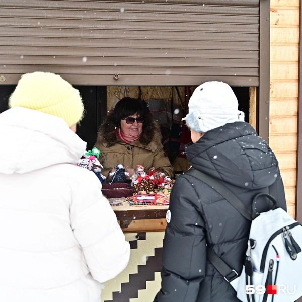 Продавец не прячется от покупателей, а укрывает свои работы от падающего снега | Источник: Василина Любимова / 59.RU