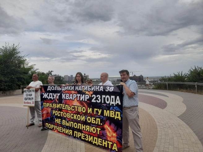 С правой стороны плакат держат дольщики Андрей Дробязко и Эдуард Попов | Источник: Ксения Сухоленко / 161.RU