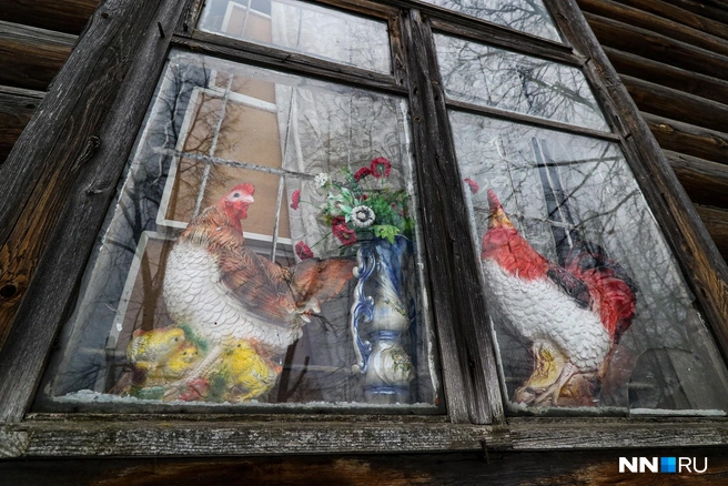 Петушки, словно настоящие, уютно уселись на окне деревянного дома | Источник: Наталья Бурухина / NN.RU