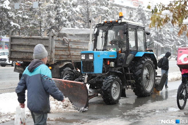 Мужчина убирает снег и грязь с тротуаров и дорог | Источник: Андрей Бортко / NGS.RU