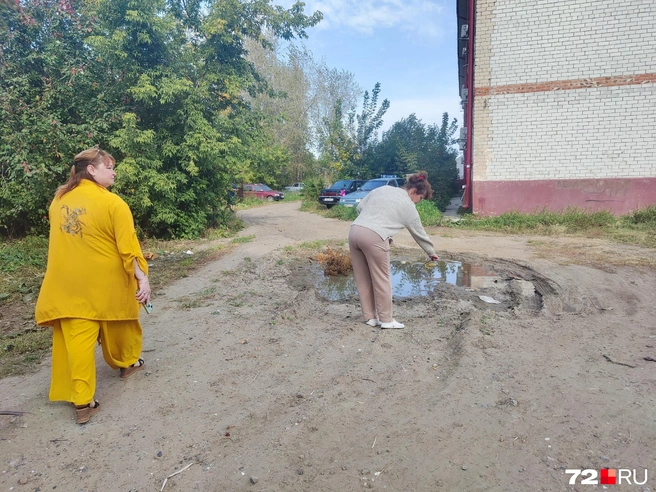 Александра и Ирина показывают разбитую дорогу за своими домами. По их словам, после дождя эта лужа превращается в огромное озеро | Источник: читатель 72.RU