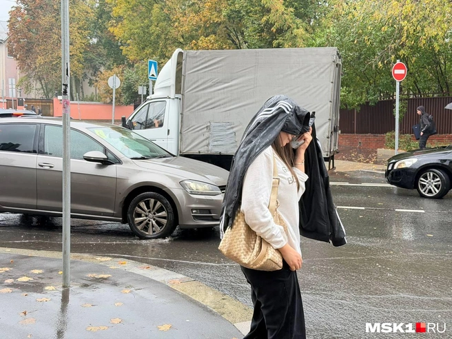 Люди прикрываются куртками от дождя | Источник: Екатерина Рябчук / MSK1.RU