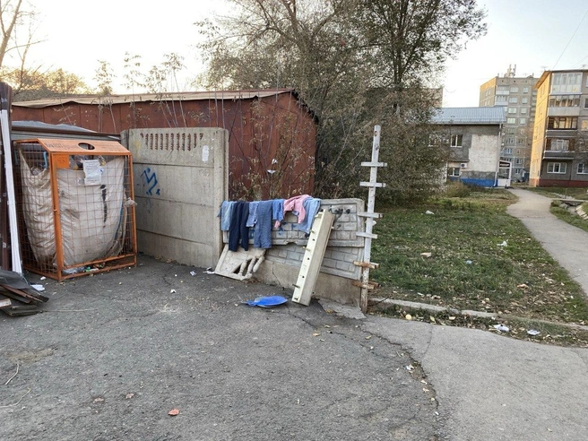 Около мусорки висят детские вещи, вероятно, чтобы их могли забрать те, кому это нужно | Источник: Ирина Господаренко / NGS22.RU