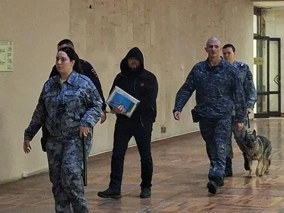 Подсудимый Сергей Кибальников следует в зал суда, прикрывая лицо | Источник: Тимофей Крылов / V1.RU