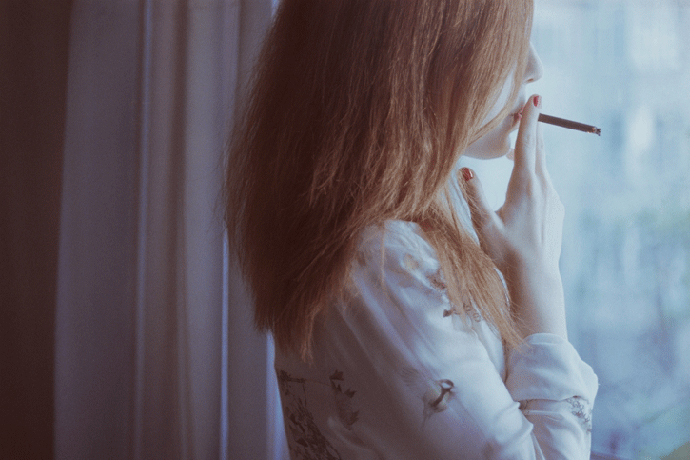 Женщина курит у окна