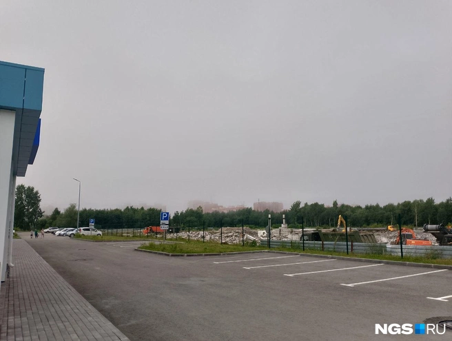 Перед поликлиникой несколько десятков парковочных мест, но утром в первый день работы почти все были свободны. За забором — стройплощадка недостроенной концессионной школы, которую как раз разбирают | Источник: Рихарда Лем / NGS.RU